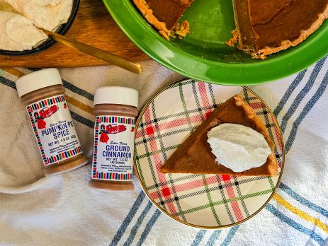 Pumpkin Pie with slice on plate and large dollop of whipped cream on top