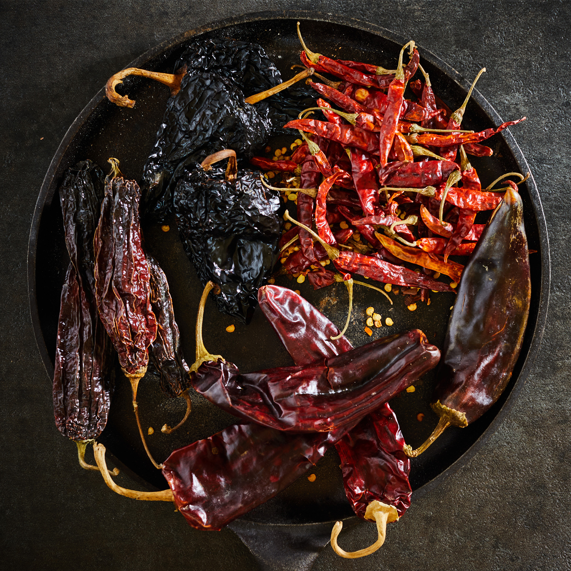 Variety of dried chili pods on wooden table